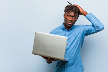 Young rasta black man holding a laptop being shocked, she has remembered important meeting.