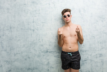 Young caucasian man wearing swimsuit showing that he has no money.