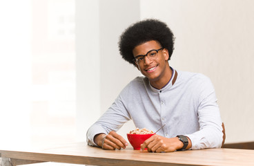 Fototapeta na wymiar Young black man having a breakfast cheerful with a big smile