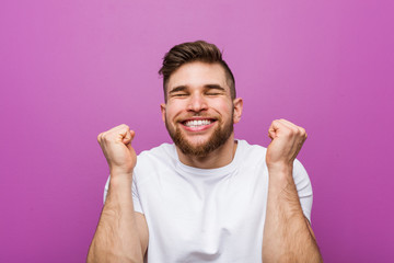 Fototapeta premium Young handsome caucasian man raising fist, feeling happy and successful. Victory concept.