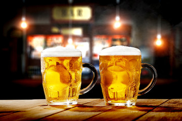 Cold fresh beer in glass on wooden table and free space for your decoration. Blurred bar interior 