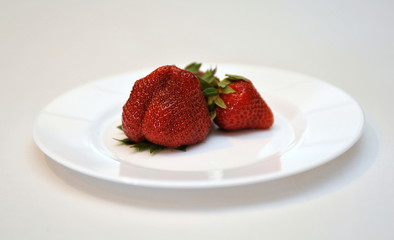 strawberry closeup on a white plate on a white background, summer