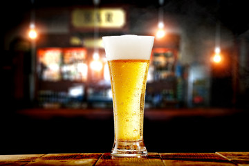 Cold beer in glass and bar background 