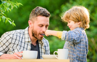 Dad and boy eat and feed each other outdoors. Ways to develop healthy eating habits. Feed your baby. Natural nutrition concept. Feeding son natural foods. Stage of development. Healthy food