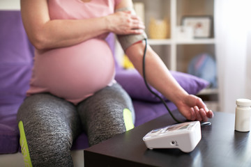 Fototapeta premium a woman measures blood pressure with an electronic pressure gauge, headache during pregnancy, poor health. selective focus on medical equipment