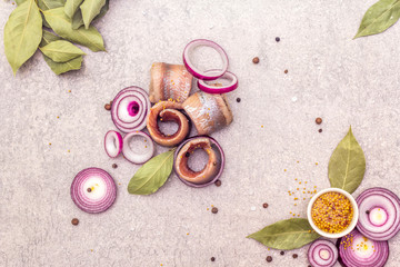 Rolled fillet of pickled Norwegian salted herring with spices and onions. Marinated fish on a stone...