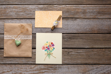 Envelope with white ribbon and two postcards with flowers.