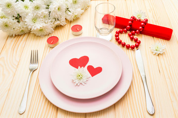 Romantic dinner concept. Valentines day, 8th march or wedding. Table setting, love hearts, gift and flowers. On wooden background