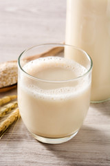 Oats milk in bottle and glass on wooden table. 