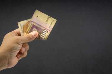 Hand holds one hundred MACEDONIA CURRENCY, Macedonian denar Bank note on black background. Selective focus