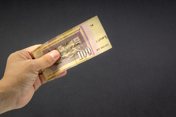 Hand holds one hundred MACEDONIA CURRENCY, Macedonian denar Bank note on black background. Selective focus