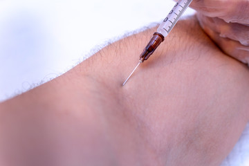 syringe injection process in a hand in gloves close up on a light blue background