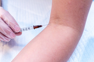 syringe injection process in a hand in gloves close up on a light blue background