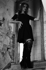 Young beautiful short hair blonde woman in black climbing the stairs, black and white photo. Side...