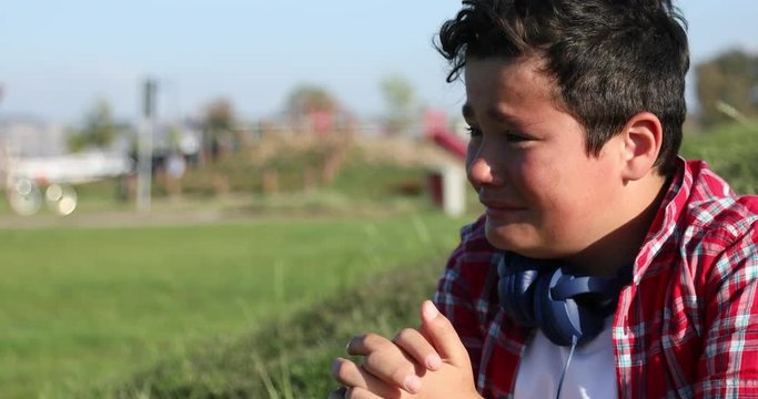 Sad preteen boy crying at the park alone