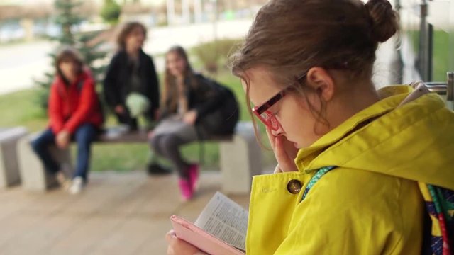 Children throw in a classmate paper, scoff. Bullies offend girl honors in the schoolyard. Teenage bullying, large portert, girl rubs glasses