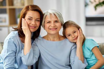family, generation and female concept - portrait of smiling mother, daughter and grandmother at home