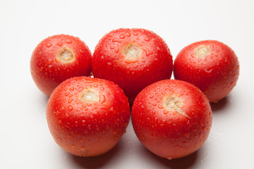 Tomates rojos, sanos y con gotas de agua sobre fondo blanco