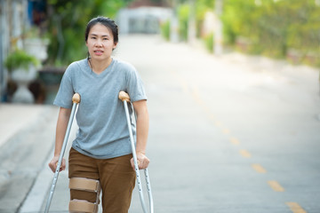 Disabled woman with crutches or walking stick or knee support standing in back side,half  body.