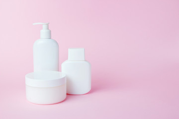 White jars of cosmetics on a pink background. Bath accessories. Face and body care concept