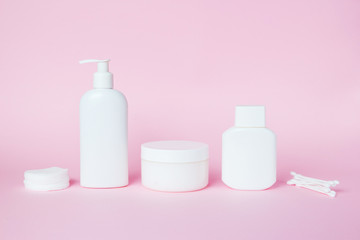 White jars of cosmetics on a pink background. Bath accessories. Face and body care concept