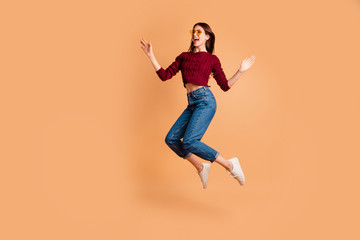 Full length side profile body size photo beautiful she her lady jump high hands arms fists raised air look empty space wear specs casual red burgundy knitted pullover isolated pastel beige background
