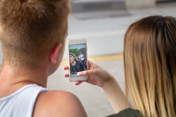 young couple watching their pictures on mobile phone, rear view