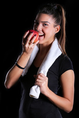 young fitness model eat an apple on black background