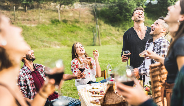 Young friends having fun drinking red wine on barbecue pic nic at garden party - Happy people eating tasty meal at country side fancy restaurant - Food and beverage concept on warm afternoon filter