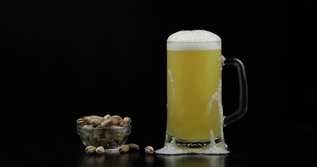 Cold Light Beer in a glass. Craft Beer close-up. Bowl of pistachios nuts.