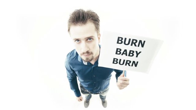 Man holding sign Burn Baby Burn 4K. Extreme wide shot top view of person head in focus while pull up a sign. White background.