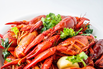A large bowl of bright red delicious braised crayfish on a white background