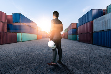 The abstract image of engineer standing in the container yard during sunrise. the concept of engineering, shipping, shipyard, business and transportation.