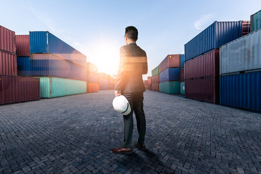 The abstract image of engineer standing in the container yard during sunrise. the concept of engineering, shipping, shipyard, business and transportation.