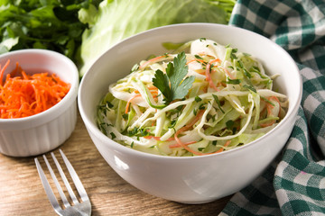 Coleslaw salad in white bowl on wooden table