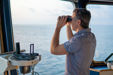Navigational officer lookout on navigation watch looking through binoculars. Marine industry. COLREG collision regulations - obrazy, fototapety, plakaty