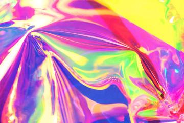Holographic iridescent surface. Copy space. Bright colorful hologram background. Wrinkled abstract texture with multiple colors. Neon surface.