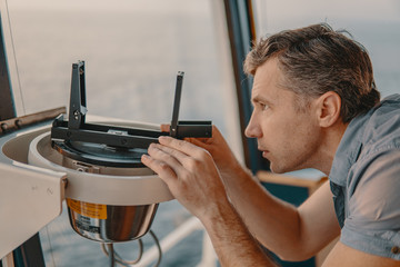 Marine deck officer taking magnetic compass error onboard of vessel at open sea. Job at sea