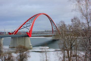 bridge with a red arch over the river in winter