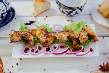Chicken wings on skewer over the white plate.