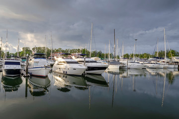 Fototapeta na wymiar Boats and yachts in a marina with dark cloud on sky. 