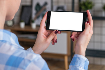 Mockup image: woman looking at black smartphone with white blank screen. Close up view of woman hands with smart phone mobile device. Mock up, copyspace, template and technology concept 