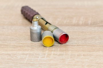 small hand-held rocket launcher with multi-colored rockets shells on a wooden background hunters...