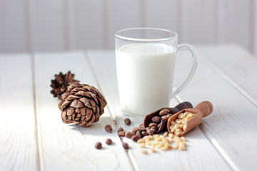 Cedar milk with pine nuts over white wooden table.