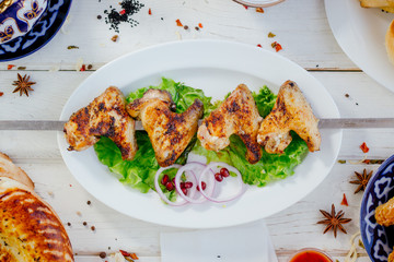 Top view of grilled chicken wings on white plate.