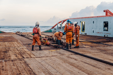 Anchor-handling Tug Supply AHTS vessel crew preparing vessel for static tow tanker lifting. Ocean...