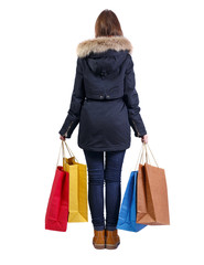 back view of woman in winter jacket with shopping bags.