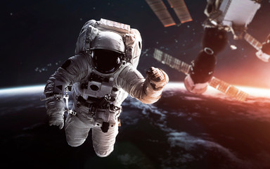 Fototapeta na wymiar Astronaut at the Earth orbit with the Space station behind. Elements of this image furnished by NASA