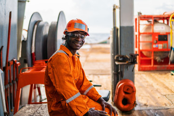 happy Seaman AB or Bosun on deck of vessel or ship , wearing PPE personal protective equipment -...