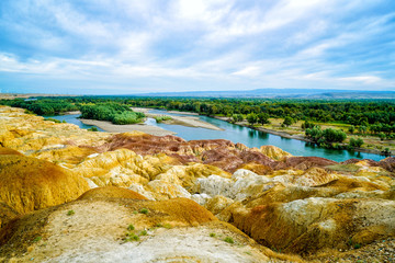 Rainbow Beach, Five Colored Hills scenic area, an oasis in the desert near Burqin. Buerjin, Altay, Xinjiang Province, China. Colorful hills and the beautiful Irtysh River. Exotic Asia Landscapes